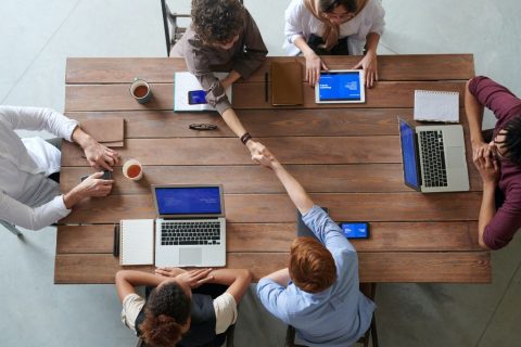 Office workers sat around a table with different hardware that is connected to the internet